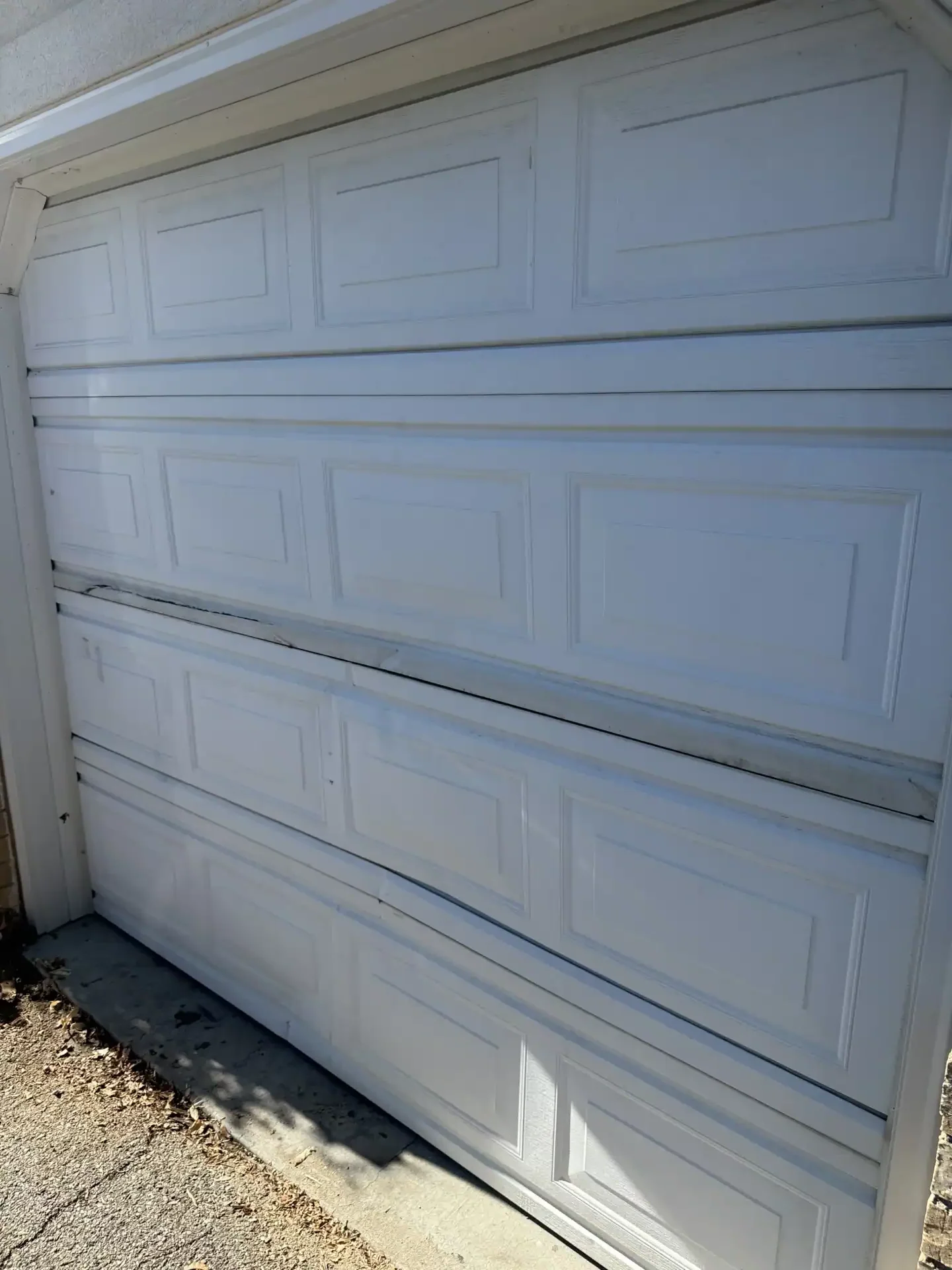Damaged garage door before replacement in Perry Utah by Beehive State Doors